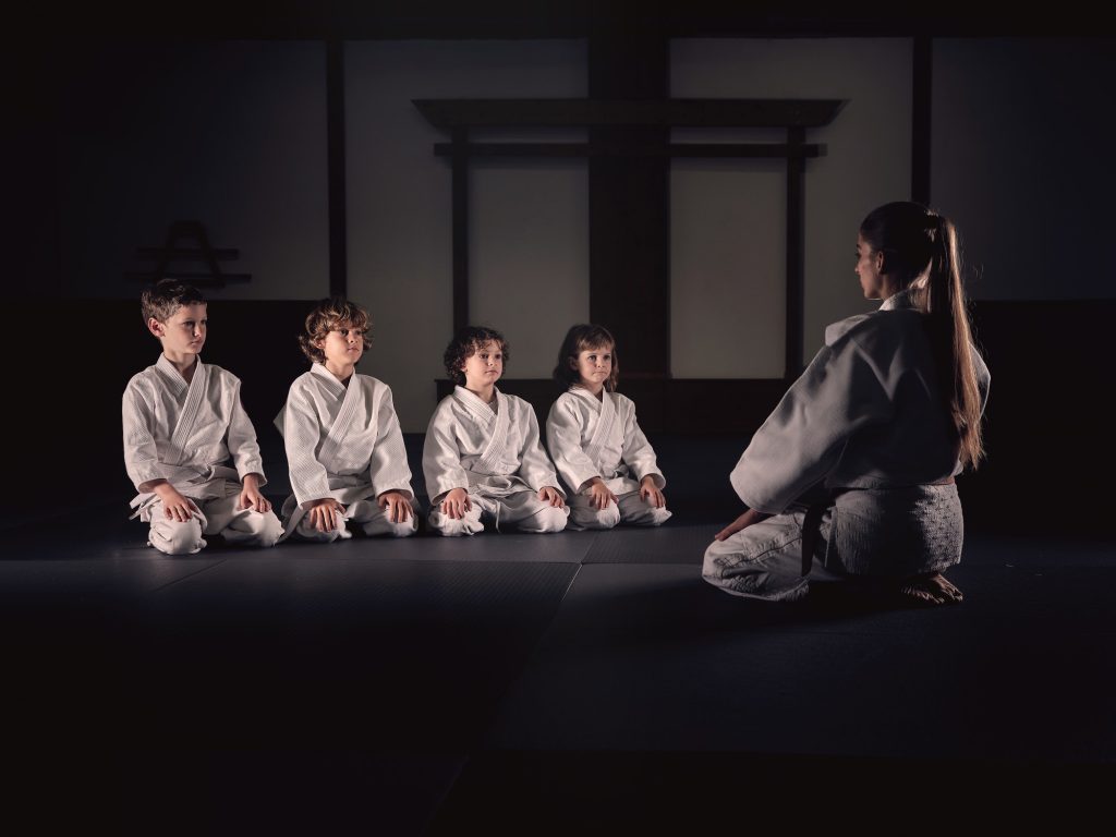 Woman and kids during martial arts training in gym